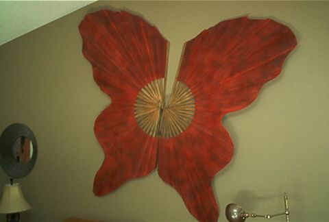 1985 Ford LTD Crown Victoria - Wall art resembling a butterfly with red wings and a central wooden fan design.