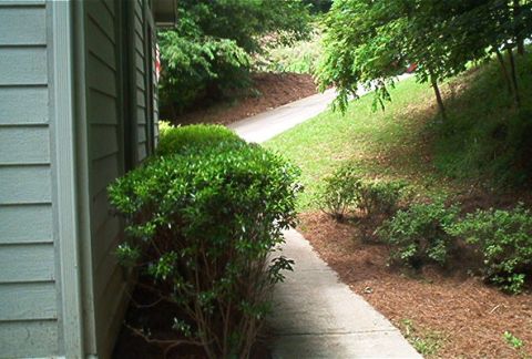 1985 Ford LTD Crown Victoria - A view of a building's exterior wall next to a paved walkway that curves uphill through a grassy area.
