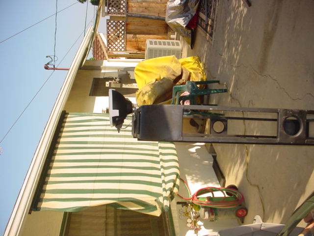 Metal rack with two lights mounted on it, outdoors next to a house