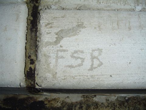 1979 Ford Bronco - A close-up of a concrete surface reveals faint markings and water stains, with a dark seam running vertically.