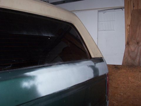 1989 Ford Bronco - The rear of a vehicle is shown with body filler applied to the quarter panel, indicating repair work.