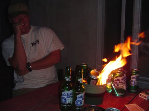 1979 Ford Bronco - A man watches as several Rolling Rock beer cans are set ablaze in a bucket on a table.