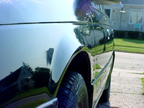 1989 Ford Taurus - A 1989 Ford Taurus is seen from the side, highlighting its body style and reflective paintwork.