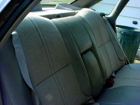 1989 Ford Taurus - Interior view of gray fabric car rear seats with a visible seatbelt buckle and stitching detail.