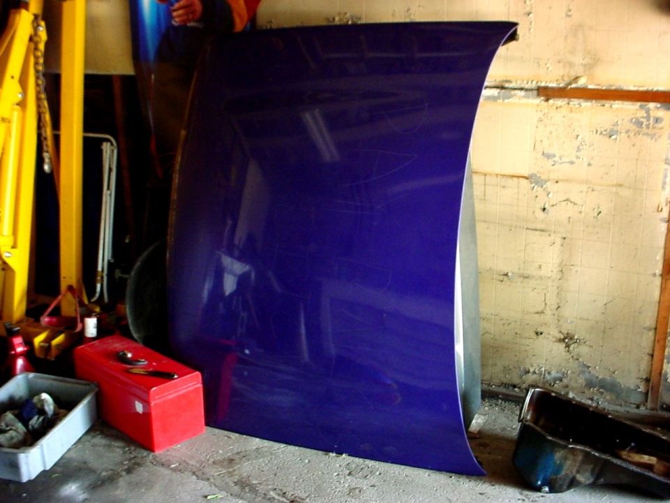 Purple car hood leaning against a wall