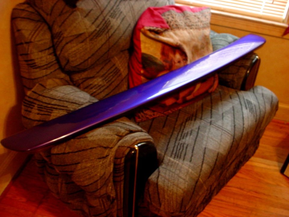 Purple car spoiler resting on a patterned armchair with pillows