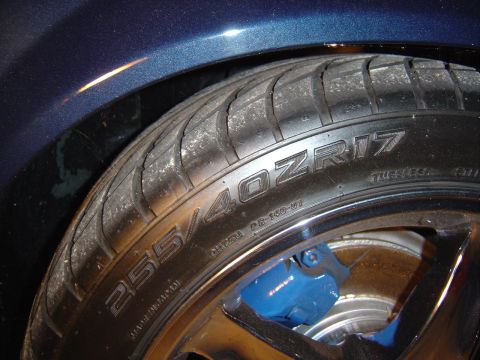 1989 Ford Mustang - A close-up view of a vehicle's tire and wheel assembly, highlighting the tire size and a bright blue brake caliper.