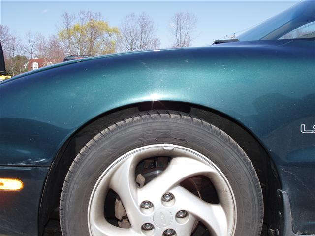 Green coupe front fender and alloy wheel with LS badge, parked outside