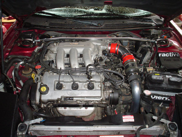 Transverse V6 engine bay of a red car with Ford valve covers and red intake