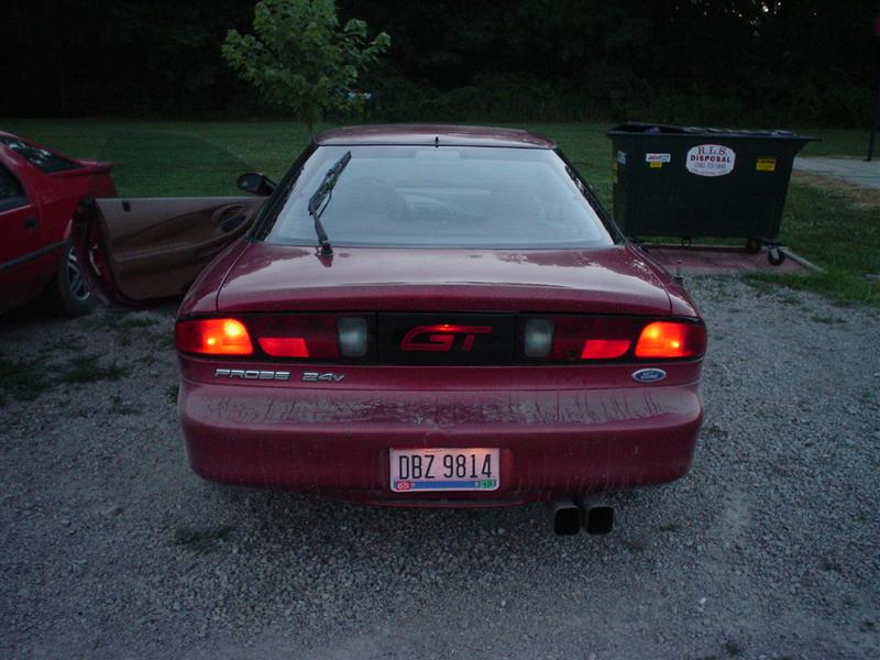 Rear of dark red Ford Probe GT with taillights on, Ohio plate DBZ 9814, parked on gravel at dusk