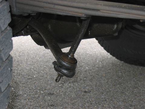 1988 Ford Bronco - A close-up view of the steering linkage and a tire on a vehicle.