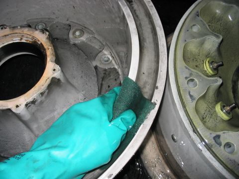 1988 Ford Bronco - Someone is cleaning brake components with a scrub pad and gloves.