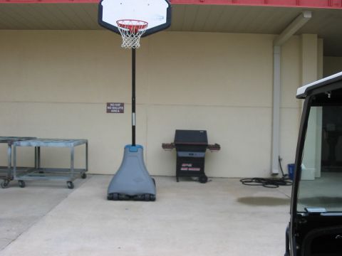 1988 Ford Bronco - A portable basketball hoop and grill are set up on a concrete patio, with a golf cart parked nearby.