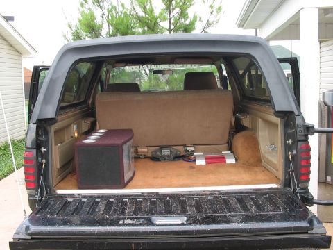 1988 Ford Bronco - The rear cargo area of a 1988 Ford Bronco shows a subwoofer box and amplifier, along with the folded-down rear seat.