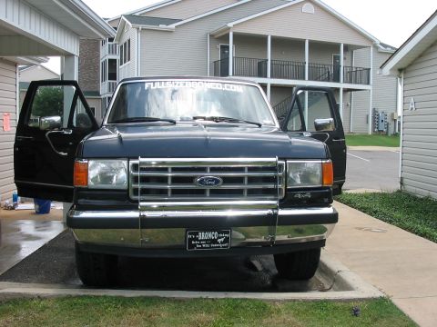1988 Ford Bronco - Front view of a 1988 Ford Bronco parked outside with its doors open.