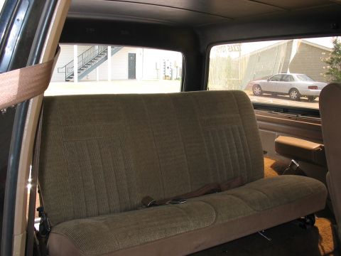 1988 Ford Bronco - Looking out the window from the back seat of a vehicle at another car parked outside.