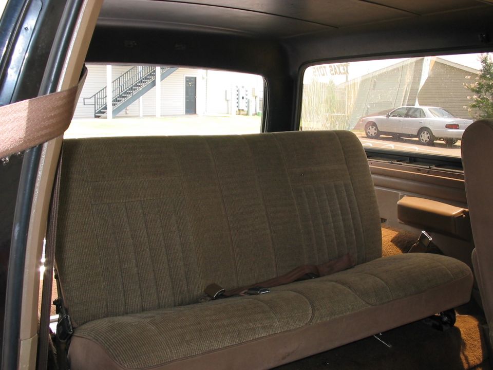 View of back seat and window showing a white sedan outside