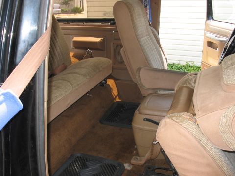 1988 Ford Bronco - Interior view of a vehicle's tan seats and brown carpet, showing the seatbelt and floor mats.