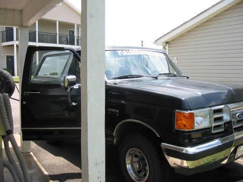 1988 Ford Bronco - This black 1988 Ford Bronco is parked under a covered area with its driver's door ajar.