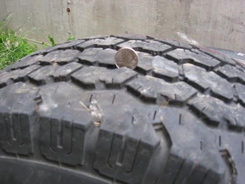 1985 Ford Bronco - Tire tread detail with a coin placed on it.