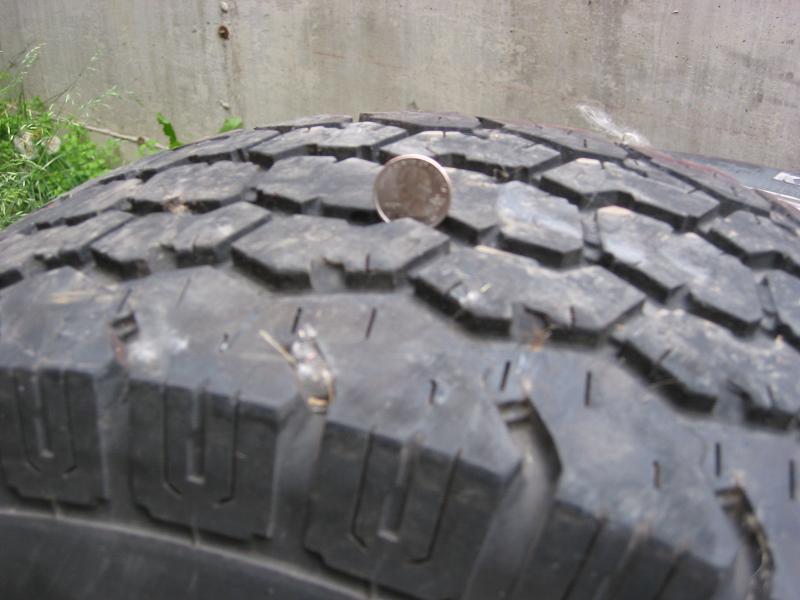 Penny inserted in all-terrain tire tread groove to measure tread depth