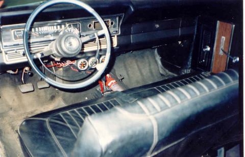 1967 Ford Fairlane - The interior of a 1967 Ford Fairlane shows a blue steering wheel, a dashboard with gauges, and a black vinyl bench seat.