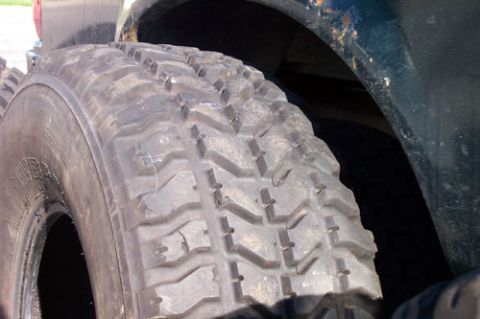 1995 Ford Bronco - Close-up of an aggressive mud-terrain tire mounted on a truck, showing the deep chunky lug blocks and siping across the tread face and shou…