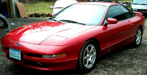 1996 Ford Probe - A red 1996 Ford Probe is parked outdoors next to another vehicle.