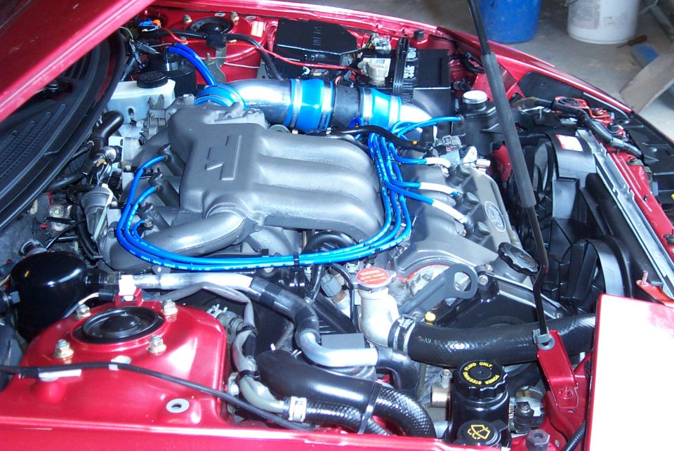 Red Ford Probe engine bay with blue plug wires and intake coupler