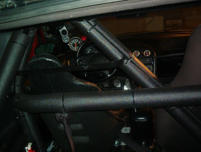Interior roll cage tubing with gauges and steering wheel visible behind