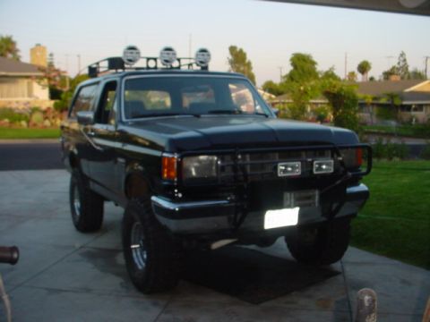 1988 Ford Bronco - Front 3/4 view of a black 1988 Ford Bronco with a roof rack and auxiliary lights.