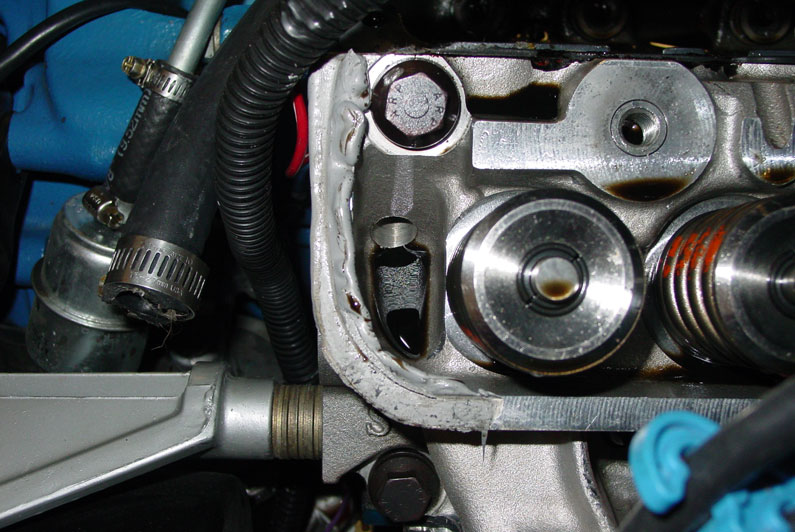 Engine cylinder head with valve cover off, camshaft bearings, RTV sealant bead and wiring visible