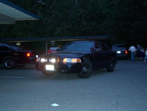 2001 Ford Crown Victoria - Front view of a 2001 Ford Crown Victoria police car, parked outdoors at dusk with other vehicles and people nearby.