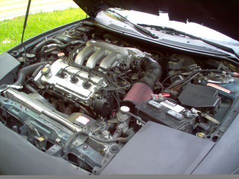 1996 Ford Probe - The engine bay of a 1996 Ford Probe shows its V6 engine, a red cone air filter, and the battery.