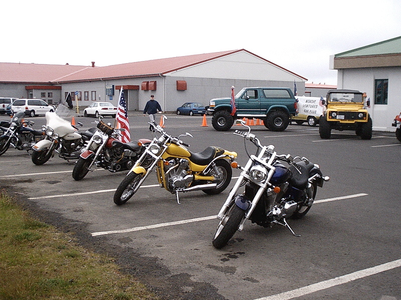 Row of cruiser motorcycles in a parking lot with a green lifted Bronco behind them