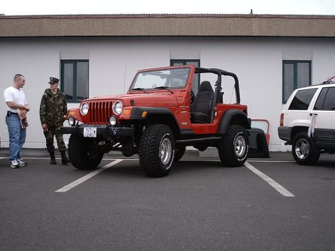 1996 Ford Bronco - A red Jeep Wrangler is parked next to a white SUV. Two people stand near the Jeep.