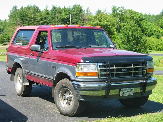 Red and silver two-tone Ford Bronco with black brush guard and roof clearance lights, front three-quarter view