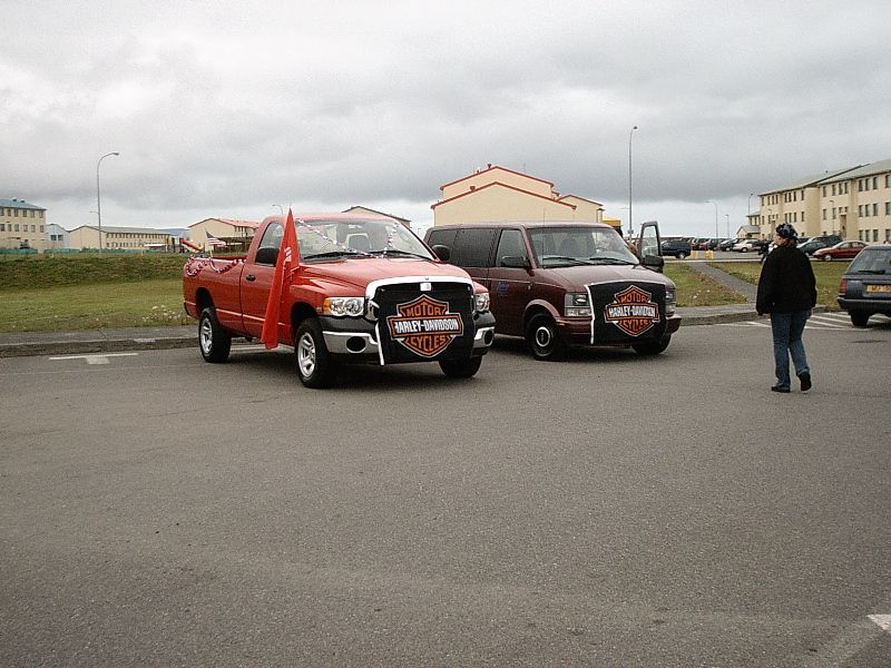 Red Dodge Ram pickup with Harley-Davidson door graphics parked next to a maroon SUV in a lot