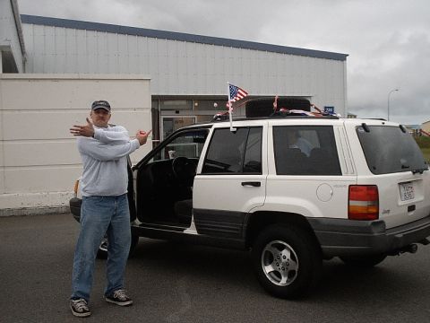1996 Ford Bronco - A white Jeep Grand Cherokee is parked outside a building, with a man standing next to it.