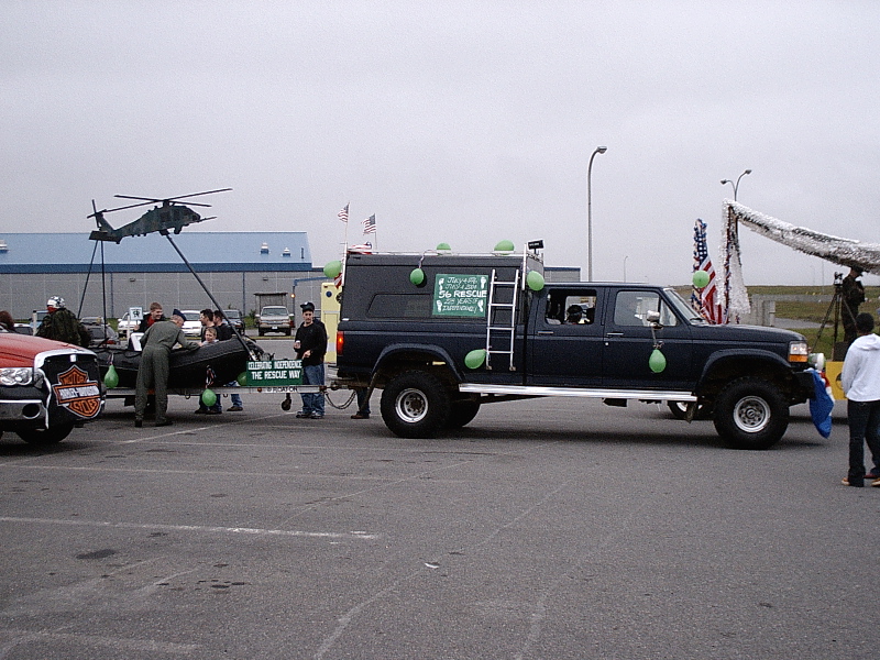 Lifted dark blue crew-cab Ford pickup with canopy and green balloons at an outdoor event