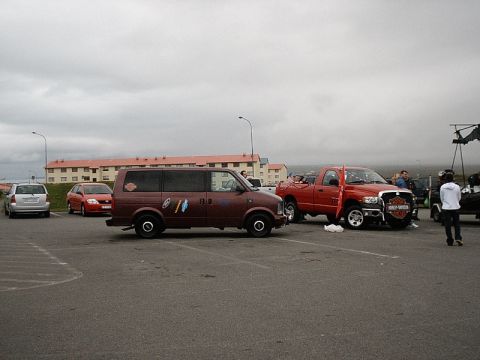 1996 Ford Bronco - Several vehicles are parked in a lot under a cloudy sky, with apartment buildings in the distance.