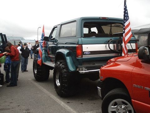 1996 Ford Bronco - Modified 1996 Ford Bronco and a red Dodge Ram 1500 are parked side-by-side, each adorned with flags.