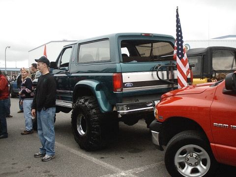 1996 Ford Bronco - A modified 1996 Ford Bronco is parked next to a red Dodge Ram, with an American flag displayed.