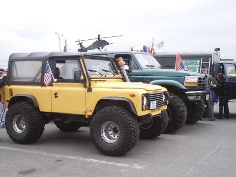 1996 Ford Bronco - Two off-road vehicles, a yellow Land Rover and a green Ford Bronco, are parked together.