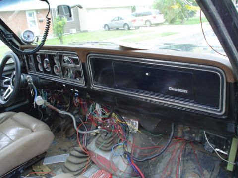 1981 Ford Bronco - Interior of a bare-shell Ford truck mid-rewire, with a tangle of loose colored wiring harness draped over the transmission tunnel and floor…