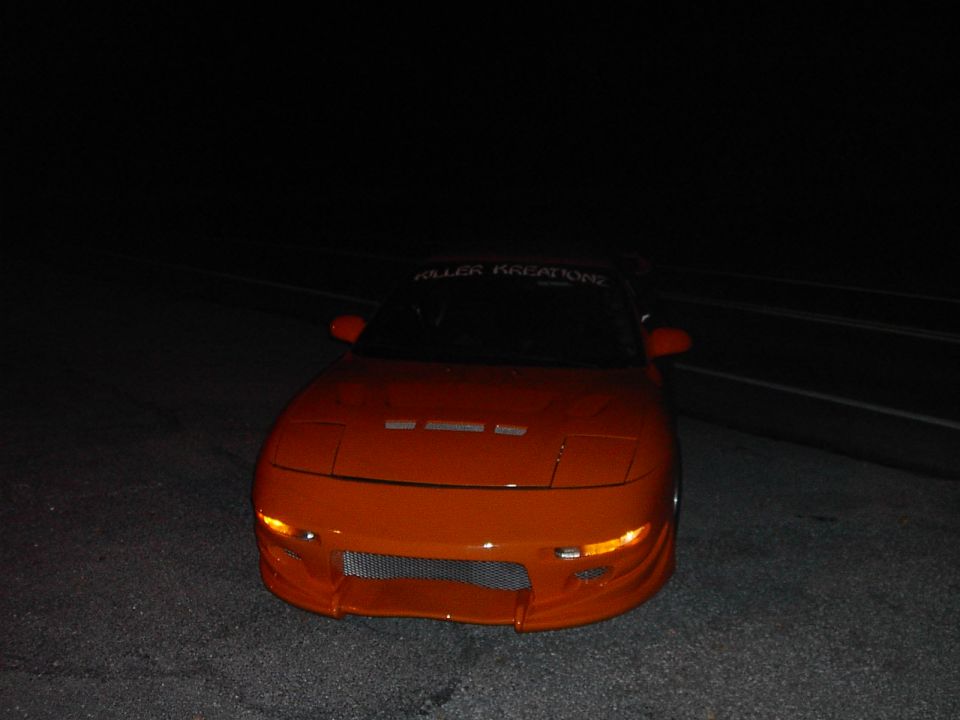 Orange sports car with pop-up headlights and 'Killer Kreations' banner
