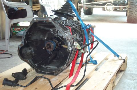 1995 Ford Bronco - A manual transmission with an attached transfer case or bellhousing sits on a wooden pallet, secured with blue and red ratchet straps. The…