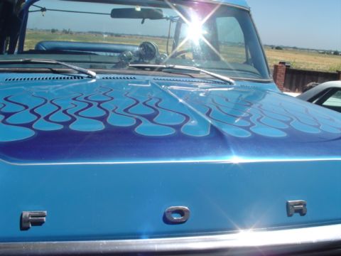 1978 Ford Bronco - Close-up of a blue truck's hood custom flame graphics and "FORD" lettering.