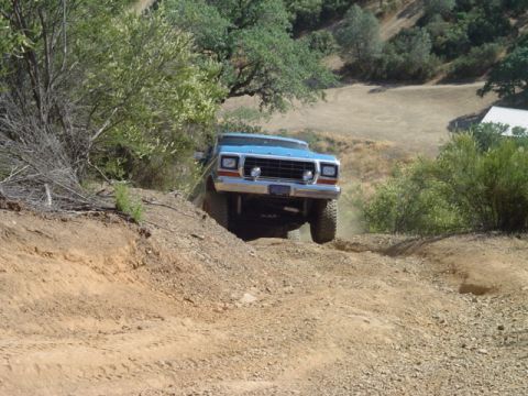 1978 Ford Bronco - A blue 1978 Ford Bronco navigates a dusty, off-road trail.