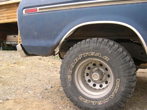 1978 Ford Bronco - Rear view of a blue 1978 Ford Bronco with a Goodyear Wrangler tire, showing the quarter panel and bumper.